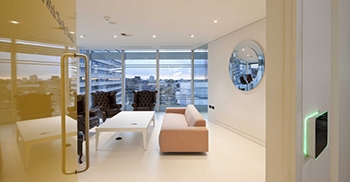 办公室设计装修：明亮的蓝色露台家具和穿过玻璃墙进入室内的长凳